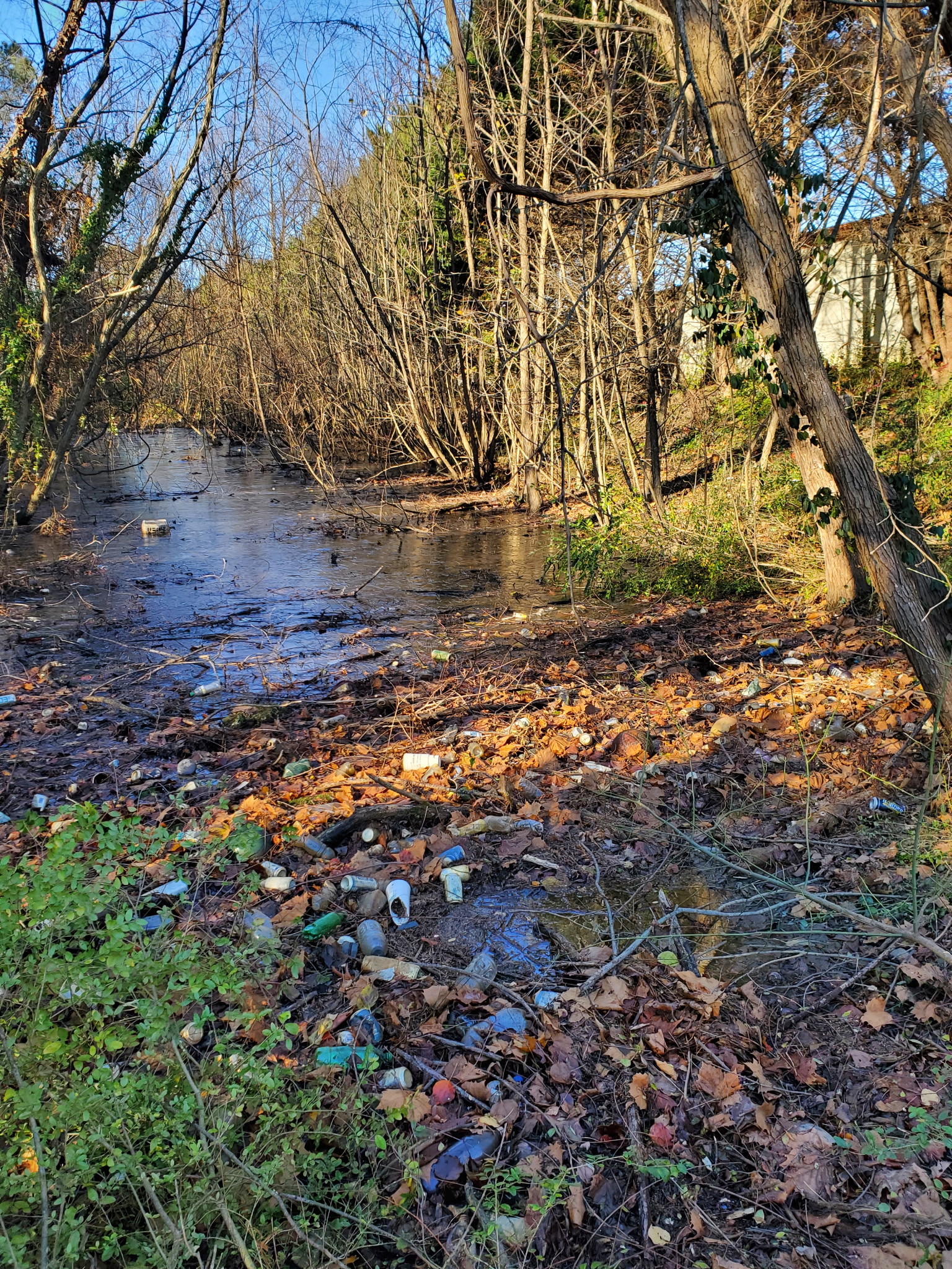 Contaminated waterway with trash and debris from unmaintained stormwater system