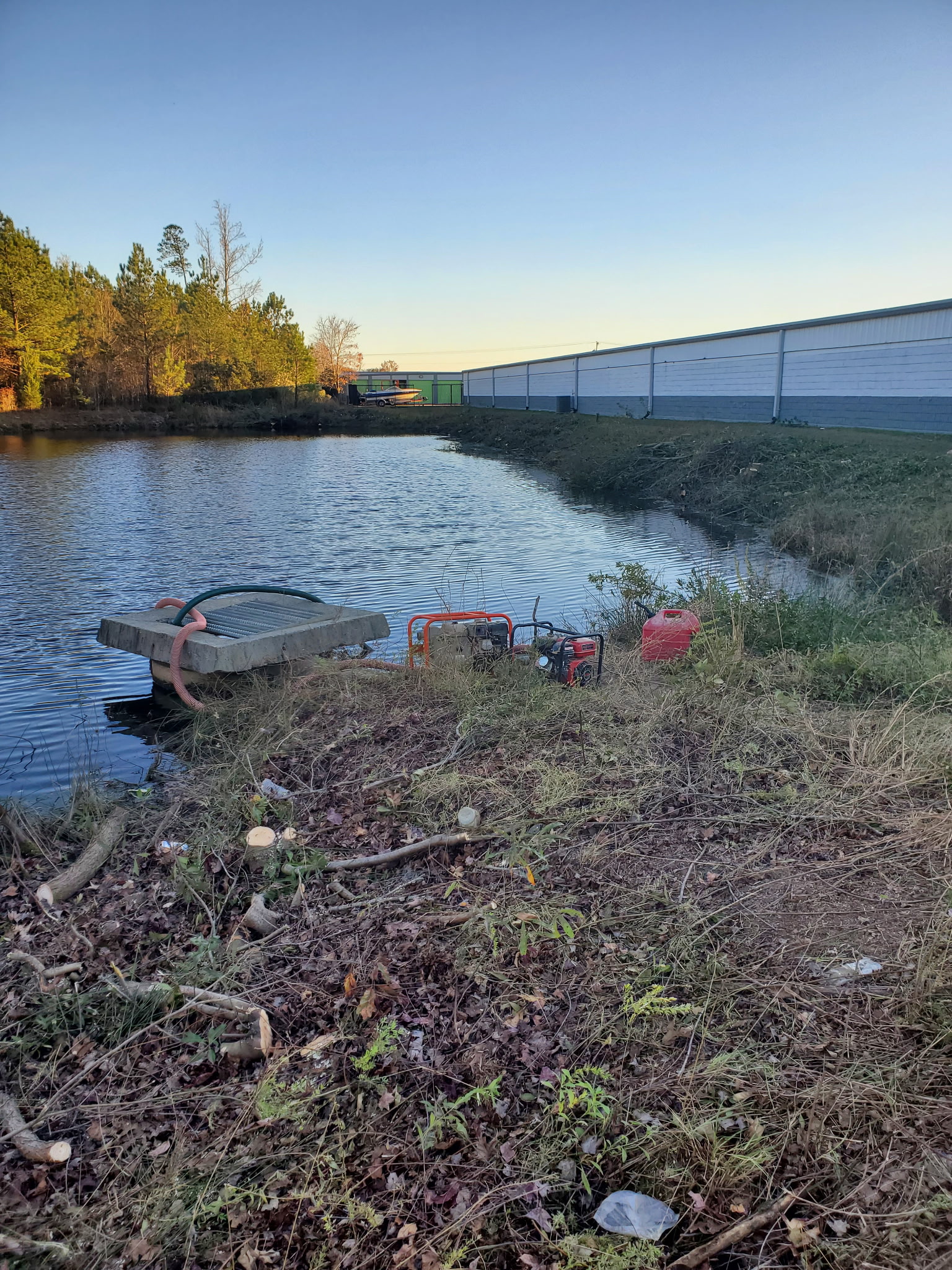 Retention pond with pump equipment needing emergency maintenance and vegetation overgrowth